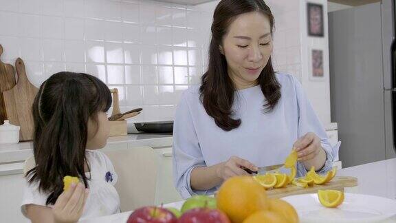 快乐的亚洲家庭小女孩享受和妈妈在厨房准备蔬菜和水果在家里健康食品