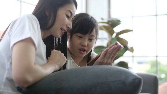 亚洲母女在客厅玩手机游戏