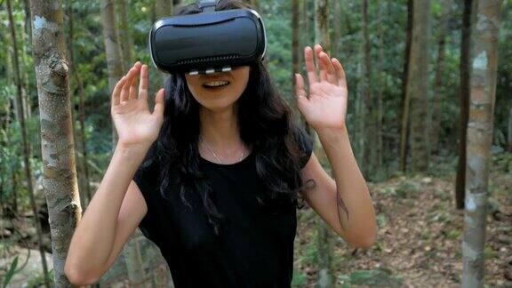 美丽年轻的黑发女人使用虚拟现实眼镜在丛林