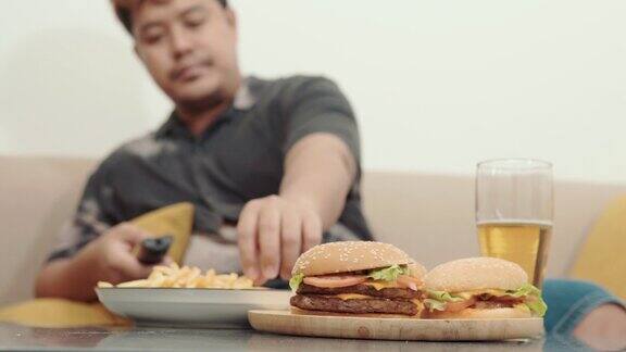 近距离拍摄男人一边看电视一边吃垃圾食品不健康的生活方式观念