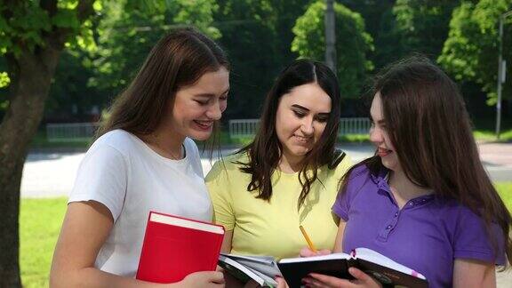 阳光明媚的一天学生三个女人在一起手里拿着书大学的女孩