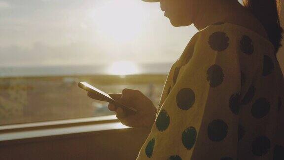 一名亚洲女性在机场窗口使用智能手机