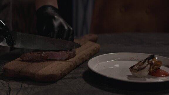 男厨师双手用刀在木板上切熟的牛排近距离观看