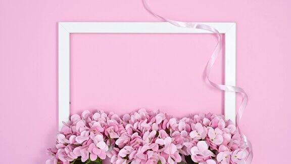 浪漫的框架与淡粉色的花朵和丝带在淡粉色的主题停止运动