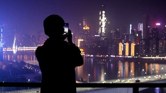 年轻人用智能手机在城市的夜晚拍照