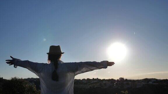一个女人站在上面看着在黎明时分举起她的手向太阳