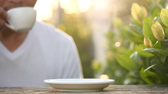 特写饮用热咖啡在美丽的早晨与蒸汽或烟的咖啡在自然背景慢动作热陶瓷白色咖啡杯和烟在旧木桌上热咖啡饮品概念