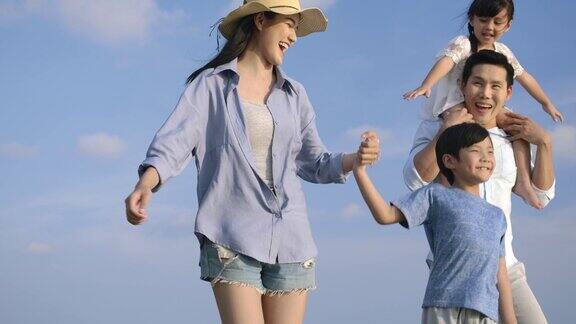 快乐的亚洲家庭享受和走在海滩上的暑假缓慢的运动家庭假期和旅游