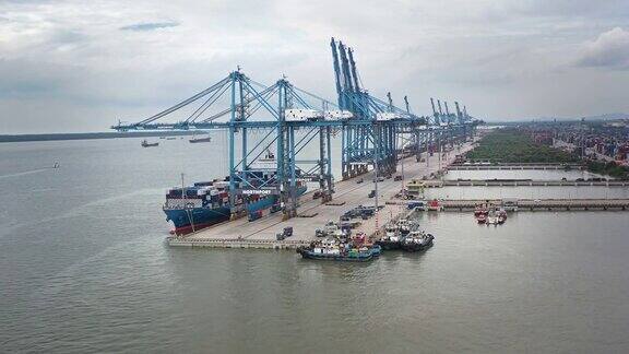 吉隆坡附近巴生港的起重机巴生港的货柜吊车正在装货的集装箱船鸟瞰图重型卡车在货仓