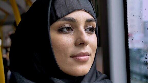 年轻甜美的穆斯林妇女的脸戴着头巾在公共汽车的雨窗口观看交通概念城市概念天气概念梦想