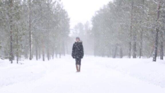 女孩在下雪的冬天走在乡间小路上