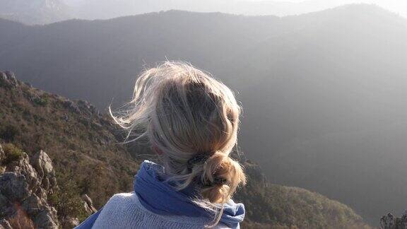 成熟的女人沿着山脊攀登眺望风景