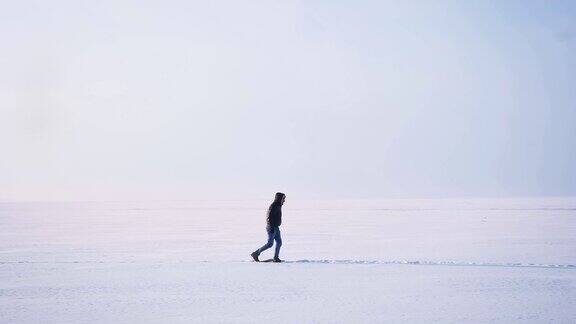 在雪地上向右行走的男性侧影的广角镜头