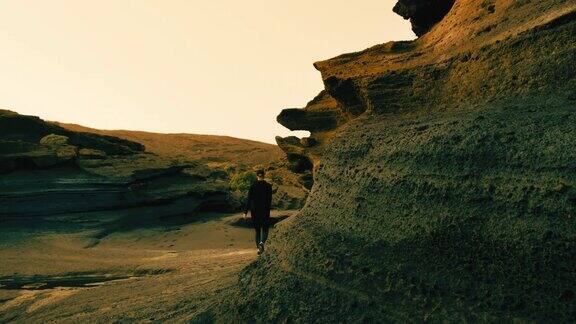 夕阳下一个女人走在火山悬崖上
