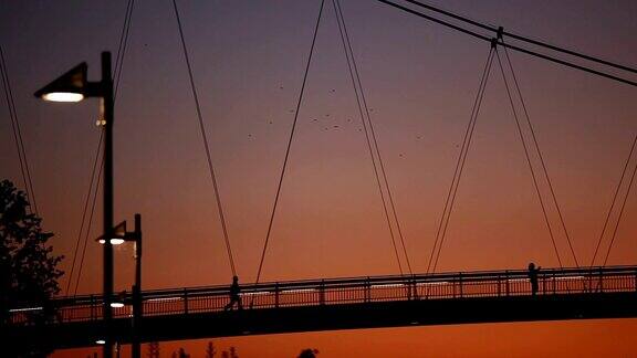 日落时分行人在德国法兰克福的人行桥上行走