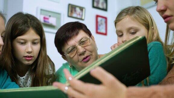 祖母和四个孙女在家里看旧相册的特写