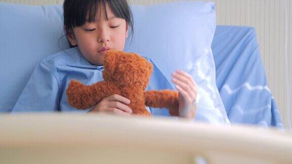 女婴在医院里喜怒哀愁的坐在床上独自看着泰迪熊紧张的时刻