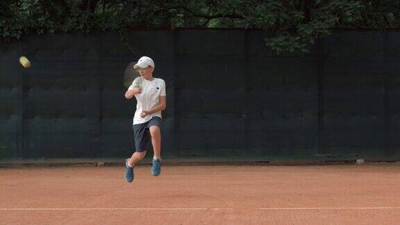 网球运动精神有抱负的孩子专注于比赛和球拍在红色的球场上击球