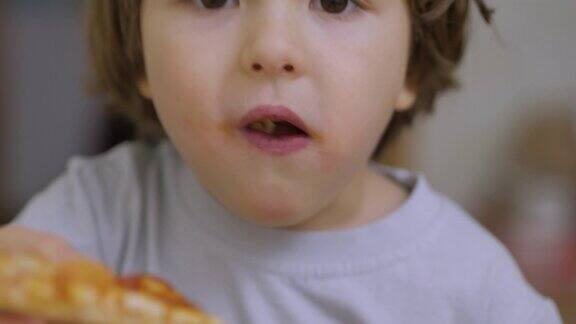 可爱的小白人男孩吃披萨饥饿的孩子吃披萨小孩在快餐店里吃东西一个吃午餐的孩子的近距离肖像面对小男孩特写