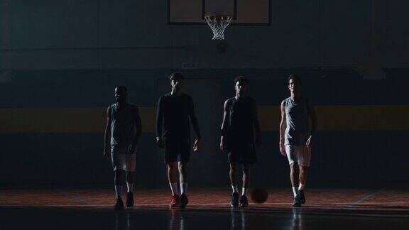年轻的职业男性球员在开始在体育馆练习篮球前走向摄像机的慢动作镜头
