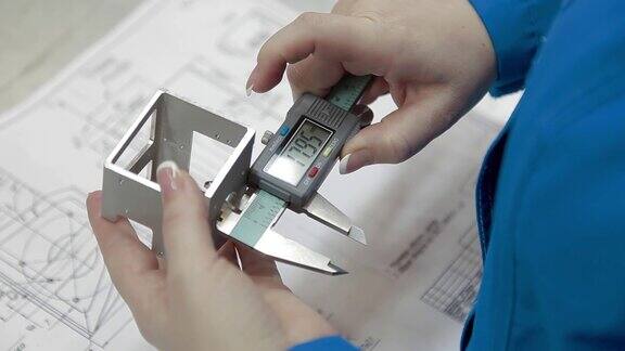 穿着长袍的工程师手握电子卡尺测量未来设备金属部分的宽度电子卡尺显示器上的数字
