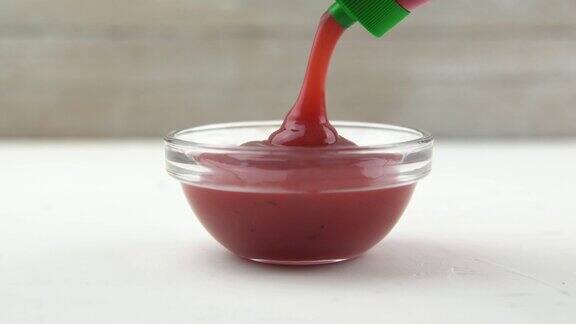 在一个透明的小碗里倒入番茄酱的特写镜头