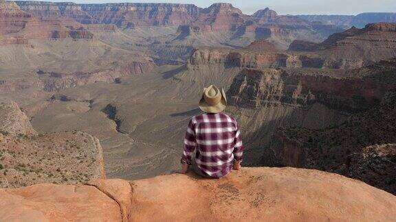 一名男子独自坐在大峡谷边缘欣赏大峡谷的美景