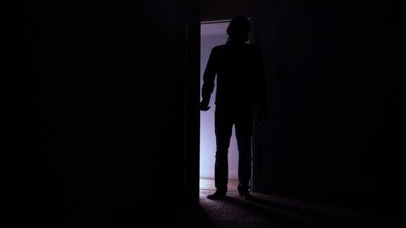一个男人打开门走进黑暗的房间剪影
