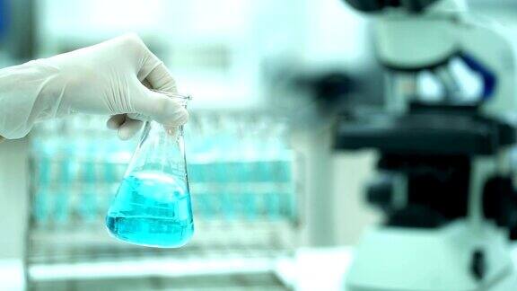 慢镜头:女科学家在实验室背景下做科学实验时摇晃装有化学物质的锥形烧瓶