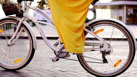 一个白色城市自行车的轮子旋转的特写有铃铛篮子和花的城市自行车清晨一个面目全非的女人骑着一辆城市自行车替身Slowmotion