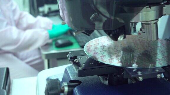 在半导体制造厂工作的技术人员穿着无菌工作服拿着硅片