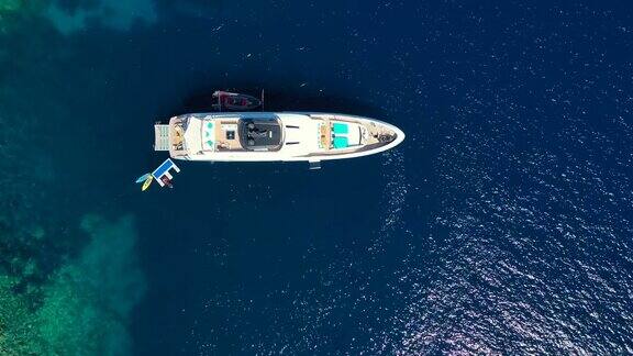 游艇停泊在热带岛屿前的碧绿海水中另类的生活方式在船上生活鸟瞰图游艇停泊在碧绿的水显示豪华财富