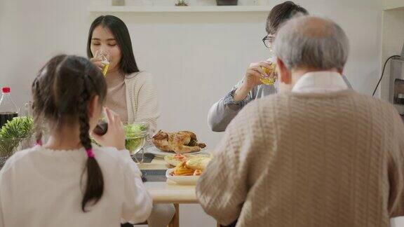 快乐的亚洲家庭共进早餐快乐的父母爷爷和可爱的女儿在家里的餐桌上一起享用早餐和祝酒美妙的时刻家庭
