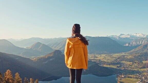 MS年轻女子走到平台的边缘俯瞰阳光明媚风景优美的山景失败者山奥地利