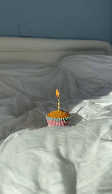 生日蛋糕床上有蜡烛和装饰祝你生日快乐在纸杯蛋糕上点根蜡烛