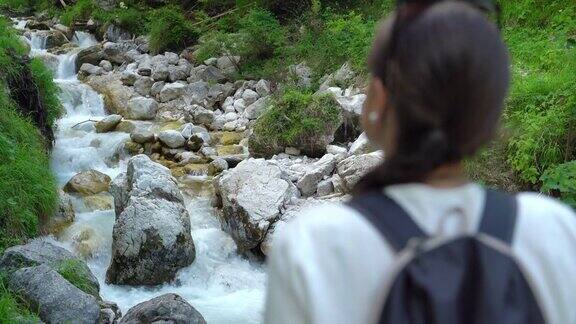 年轻女子在徒步旅行中看着流水