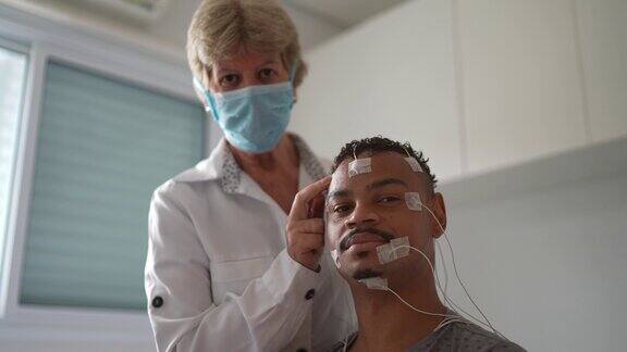 医生用口罩将电极植入病人头部进行医学检查的画像