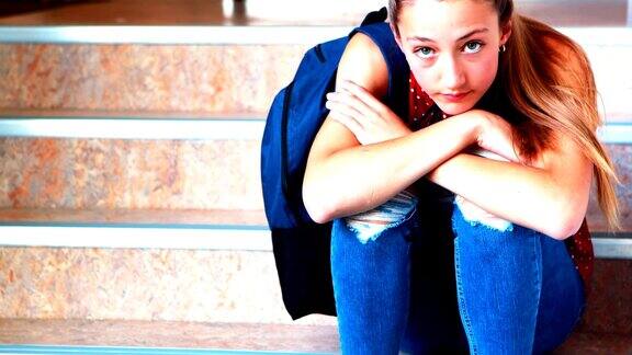 悲伤的女学生独自坐在楼梯上