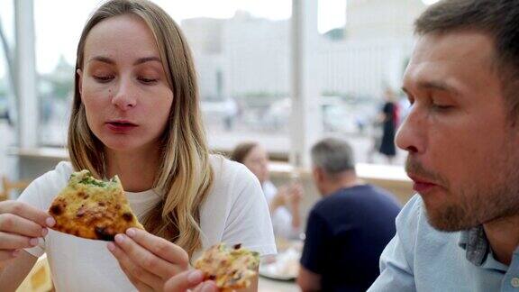一对情侣在户外吃披萨面带微笑他们在一家户外咖啡馆分享披萨