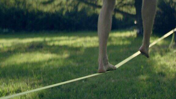 光着脚在松弛绳索上保持平衡的人夏日午后的公园