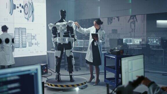 机器人开发实验室:女科学家使用数字平板电脑研究机器人外骨骼原型工程师设计Exosuit来帮助残疾人工人举起货物