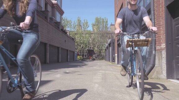 一对年轻的情侣骑着自行车穿过一条小巷