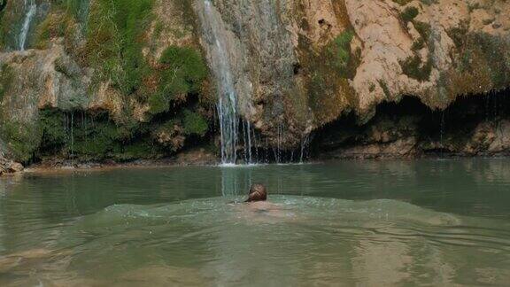 快乐女孩和森林瀑布游客年轻女子在天然河流中游泳