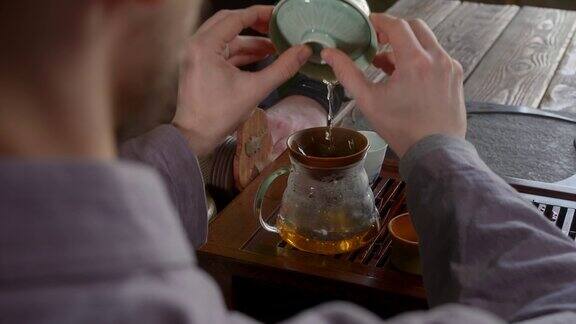 茶艺师将刚沏好的茶从盖湾倒进木茶板上的玻璃壶里