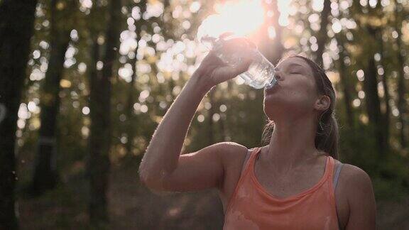 疲惫的女运动员在大自然中饮用淡水