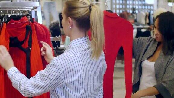 在商场里售货员帮助一位年轻女子挑选衣服