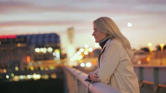 一个年轻女子站在一座夜城的桥上若有所思地望着远方