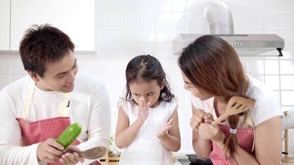 4k慢镜头年轻的亚洲父亲母亲和女儿快乐和有趣的烹饪在现代白色厨房女儿做饭时心情愉快