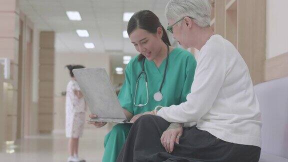医生仔细地向老年患者讲解充电器上的医学检查结果年轻的亚洲女护士护理人员支持与老年妇女病人交谈帮助解决问题医院保健
