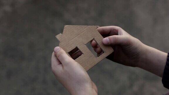 无家可归的男孩拿着一个纸板房子